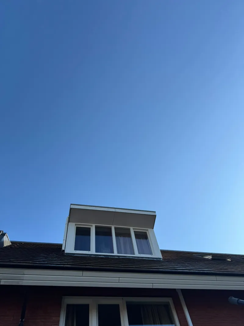 Dakkapel met schone ramen tegen een strakblauwe lucht